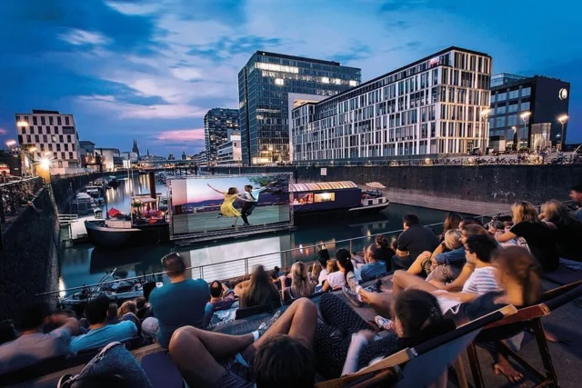 Start in den Sommer – die Wochenendfreuden vom 23.-25.05.2025
Auch wenn sich der schon anklopfende Sommer kurzfristig wieder zurückgezogen hat, feiert das Open-Air-Kino im Rheinauhafen an diesem Wochenende zum 20. Mal den Start in die von vielen herbeigesehnte Saison. Ab sofort wird an 120 Tagen Kino, Kunst, Comedy und Musik gezeigt. Nach dem ausverkauften PreOpening am Donnerstag könnt Ihr neben dem gigantischen Blick auf den Dom auch den Film Better me, die Geschichte von MegaStar Robbie Williams, genießen. Und zwar in der Originalversion. Was sonst so alles bei uns Viertel passiert, könnt Ihr hier lesen: www.meinesuedstadt.de. 
Text: Gaby DeMuirier/ Bild: Bay GmbH